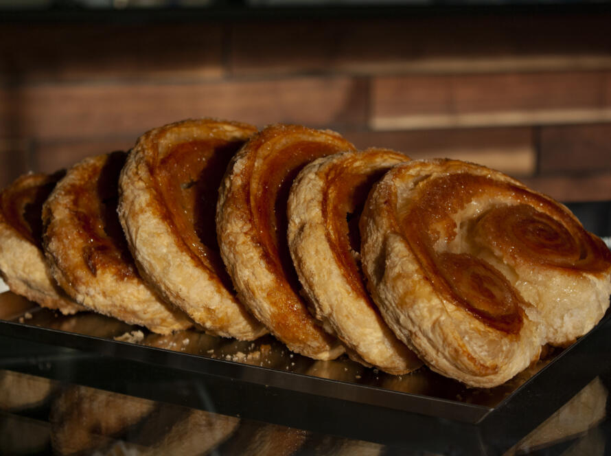A tray of golden-brown pastries with flaky layers displayed in The Bagel Legacy bakery in Purcellville.