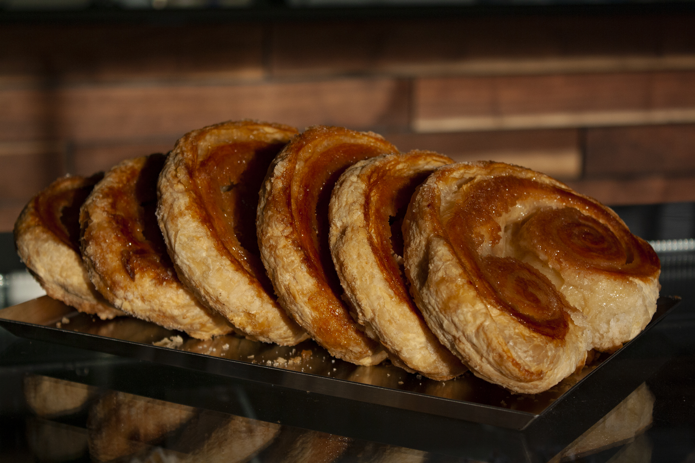 A tray of golden-brown pastries with flaky layers displayed in The Bagel Legacy bakery in Purcellville.