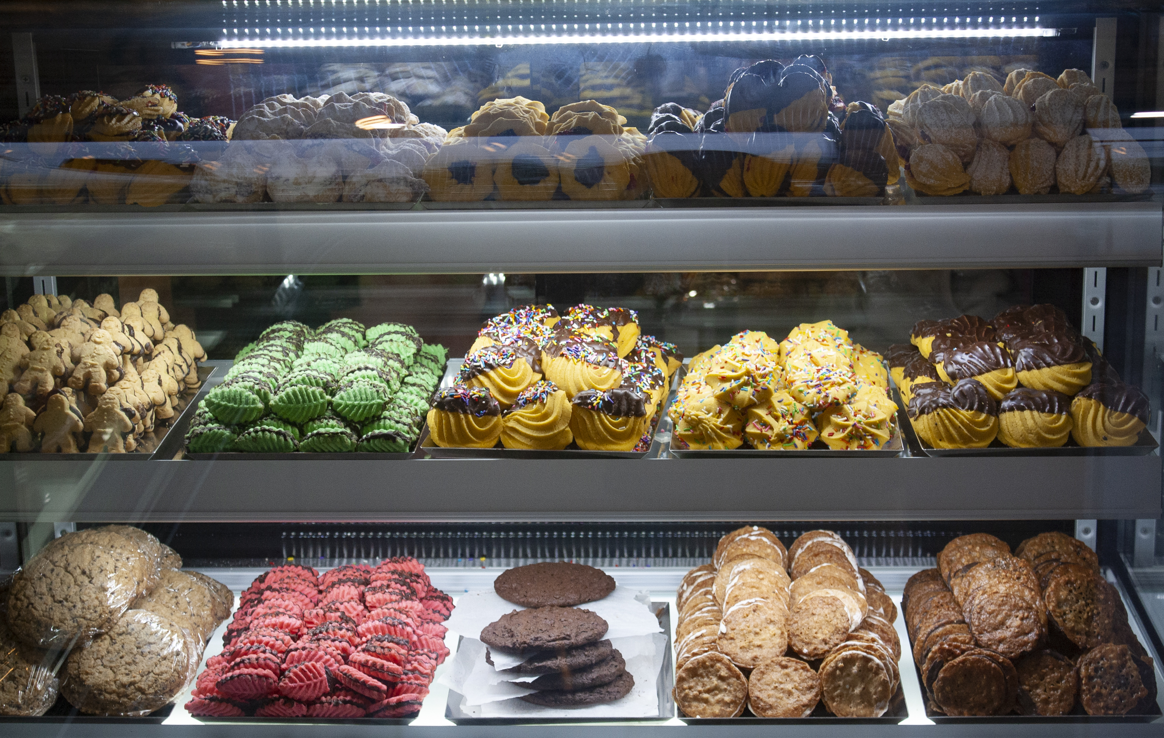 Glass bakery case filled with colorful cookies, pastries, and assorted baked treats on display.