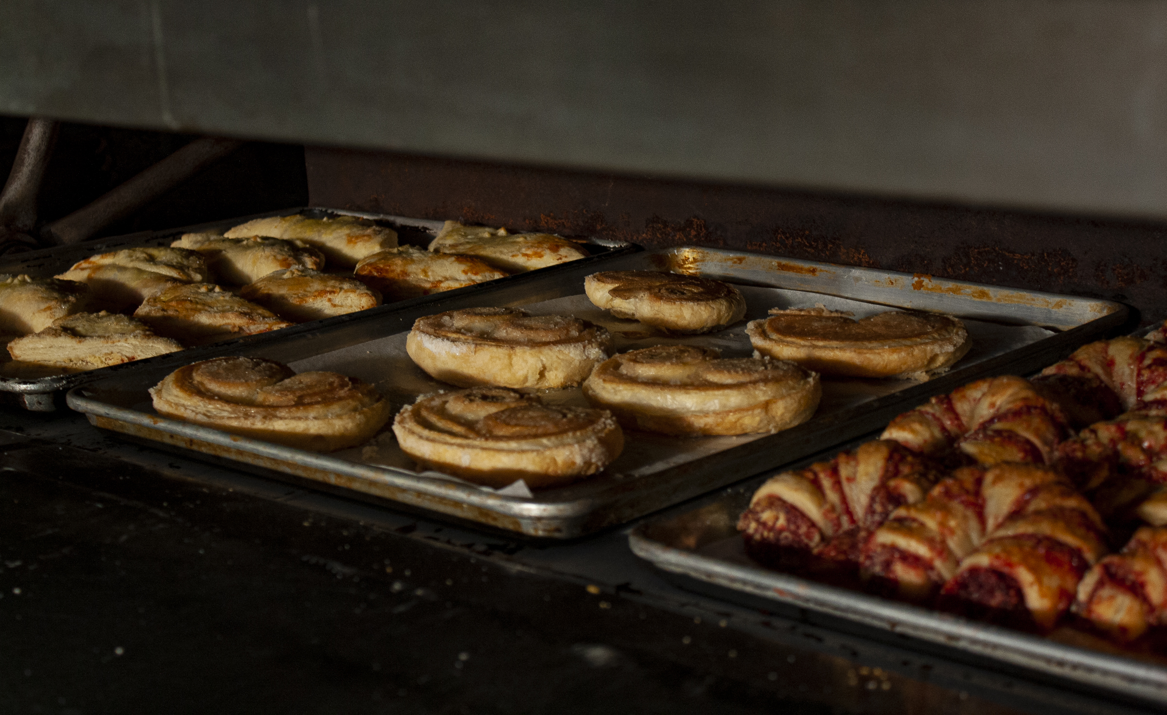 Trays of pastries baking in an oven, showing the transformation from dough to delicious at Bagel Chicks.