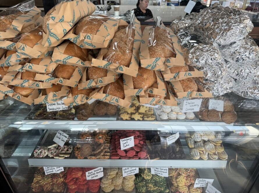 Stacks of Bagel Chicks bagels packaged in paper sleeves on a bakery counter, showing the growing demand as the new location serves the community.