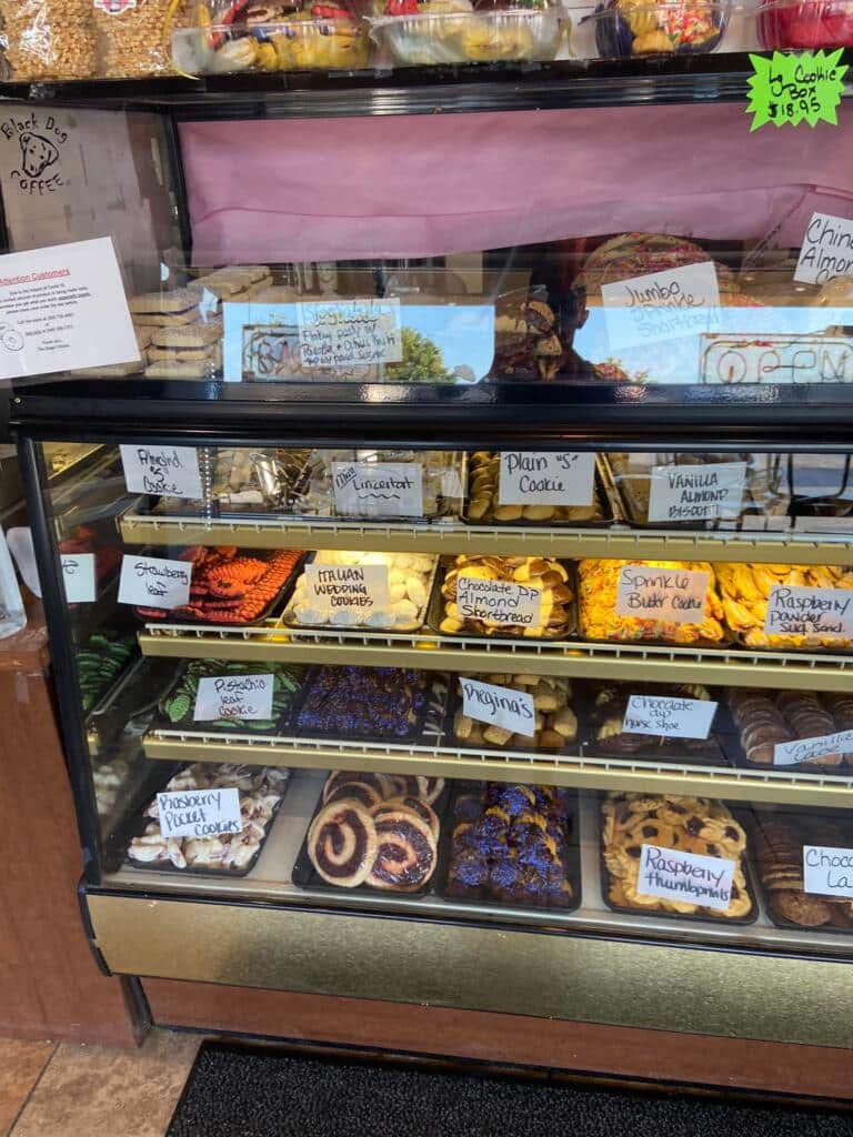Bakery display case filled with labeled cookies and pastries, showing Bagel Chicks growing and expanding to a new location that supports the community.