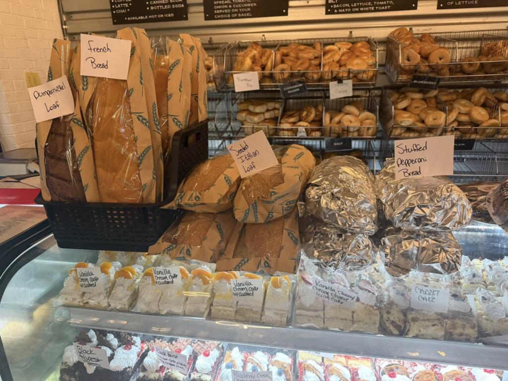 Packaged loaves of bread, wrapped baked goods, bagels, and dessert slices displayed inside Bagel Chicks in West Virginia.