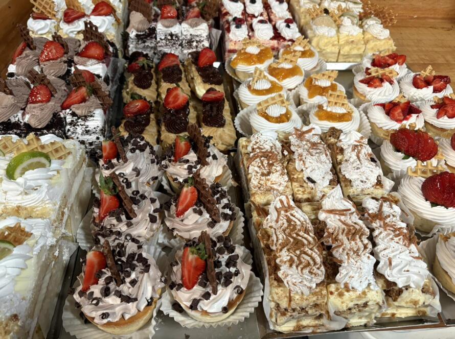 Assorted cakes and pastries at Bagel Chicks in Ranson, West Virginia, topped with strawberries, whipped cream, chocolate, and fruit fillings.