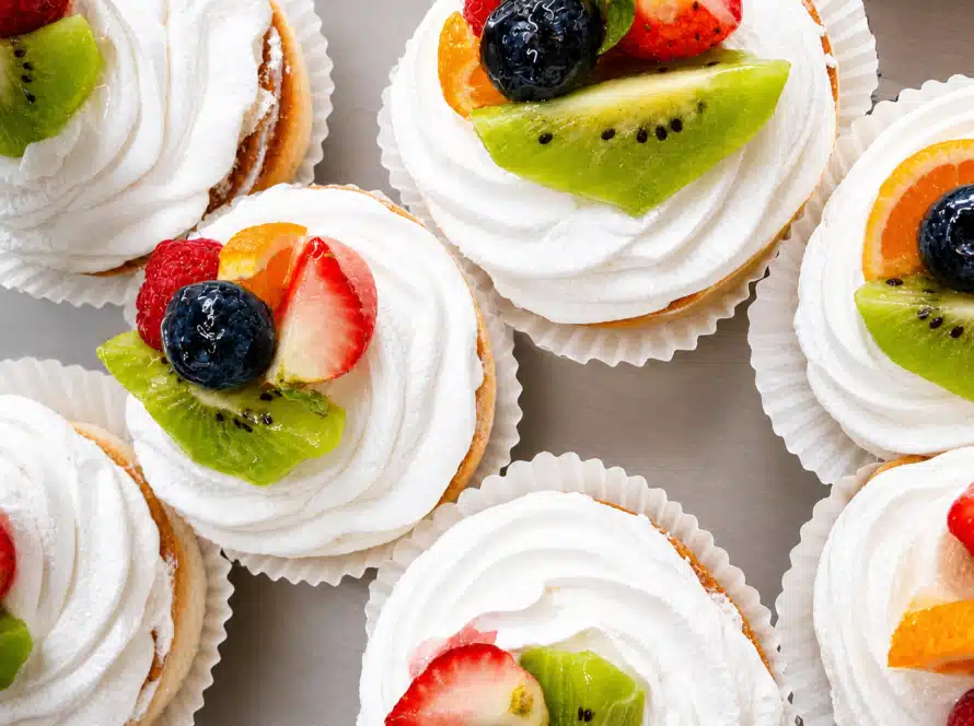 Fruit-topped cream pastries with strawberries, kiwi, blueberries, and whipped topping from the Bagel Chicks Menu.