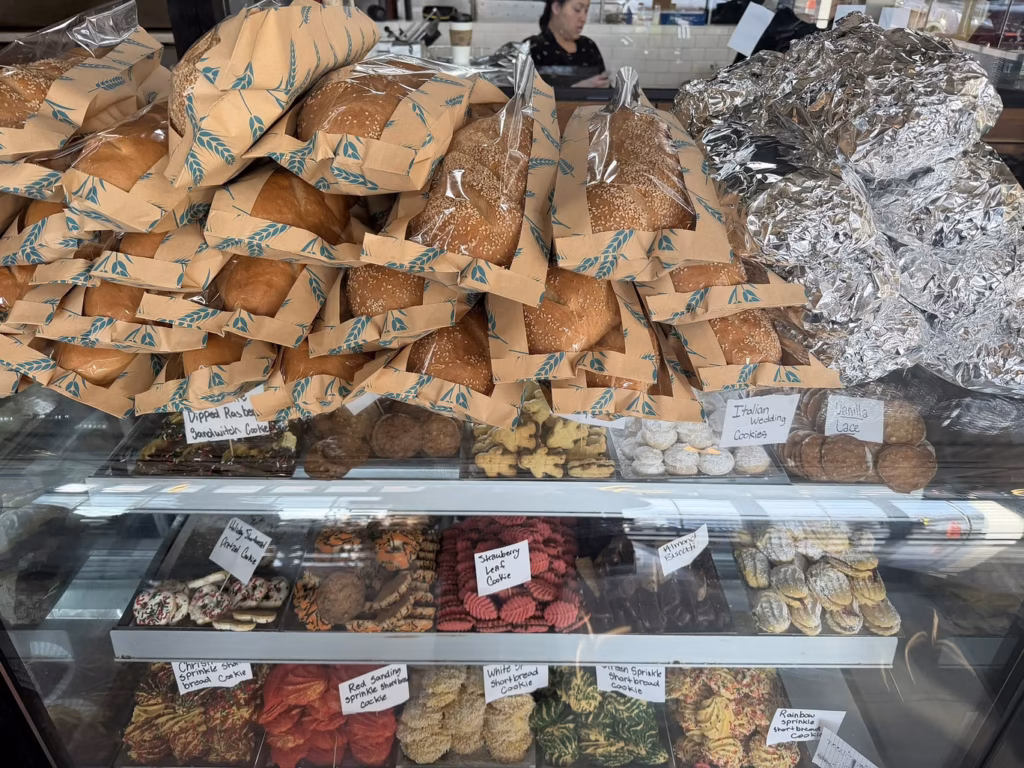 Bakery counter with wrapped bread loaves, Italian wedding cookies, lace cookies, and colorful shortbread cookies showing the evolution of local food culture in West Virginia and Virginia.