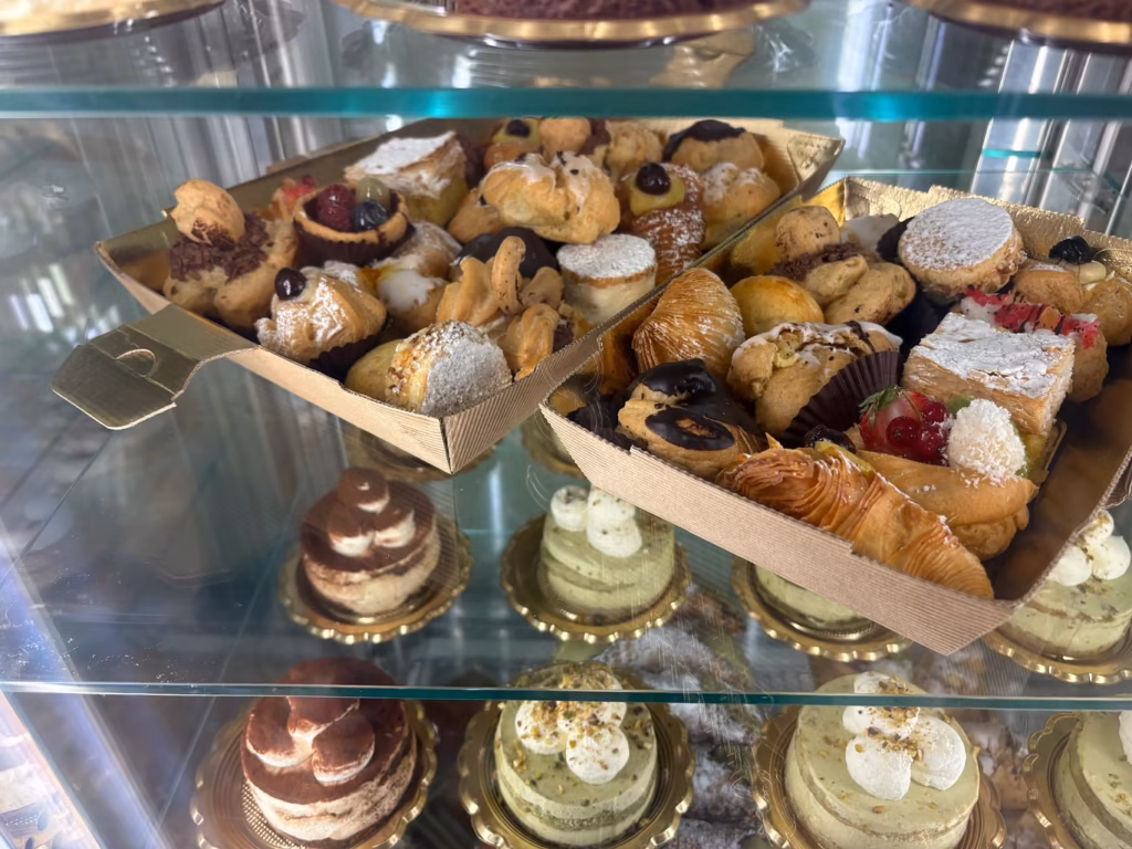 Display case filled with assorted pastries, mini cakes, croissants, and cream-filled desserts representing craft food in West Virginia and Virginia.