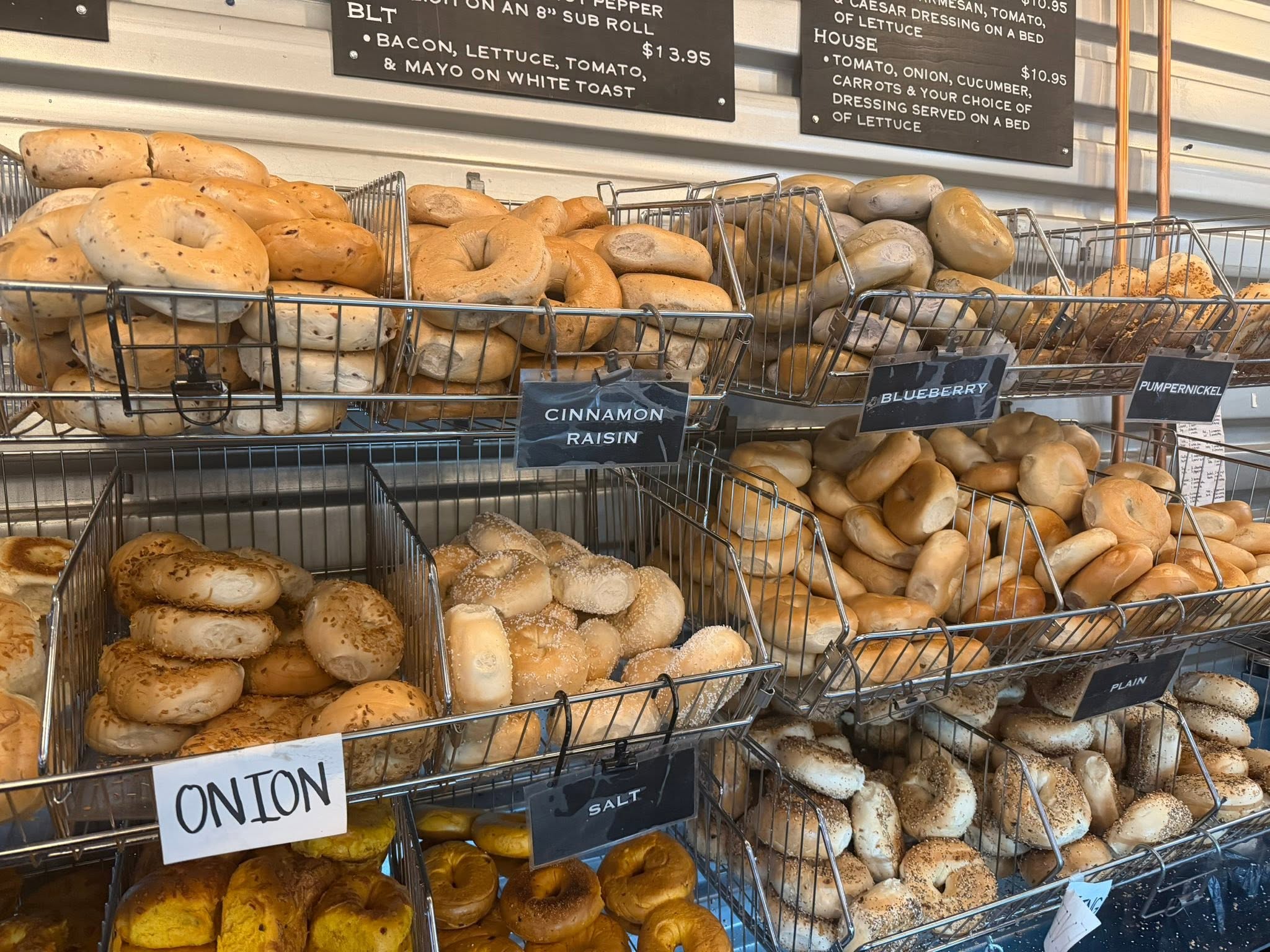 Multiple varieties of Bagel Chicks bagels displayed in labeled baskets at the West Virginia shop.