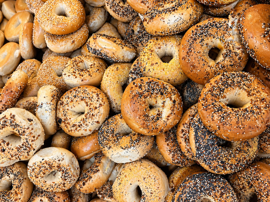 Pile of plain and seeded bagels with golden-brown crusts